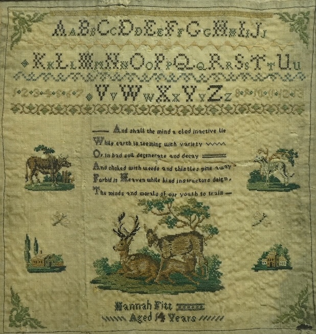 A Framed 19th century alphabet needlework sampler, by Hannah Fitt aged 14 years, (undated).worked with alphabet and numerals above a verse, surrounded by finely worked cartouche of a cow, dog, two houses and butterflies